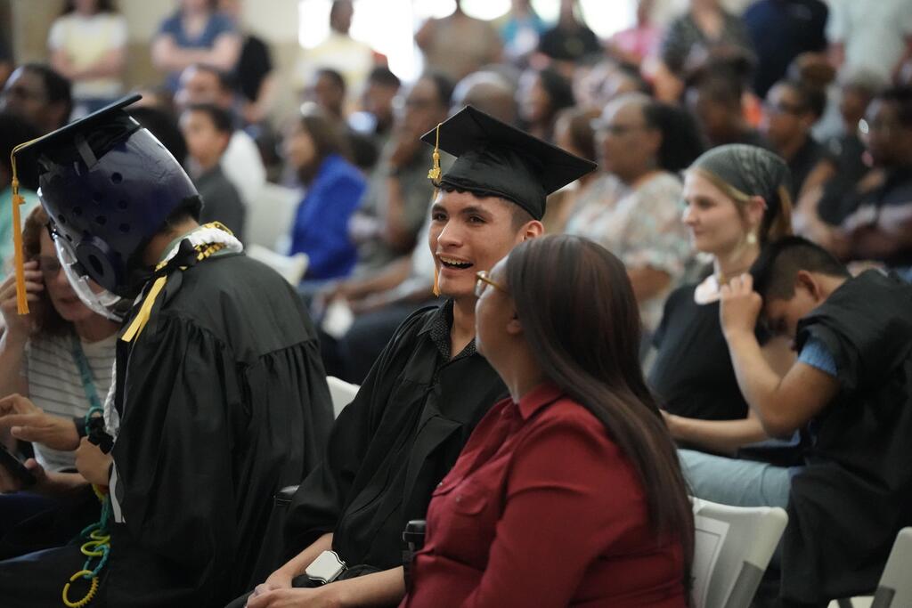 Student in graduation cap and gown smiling at ceremony
