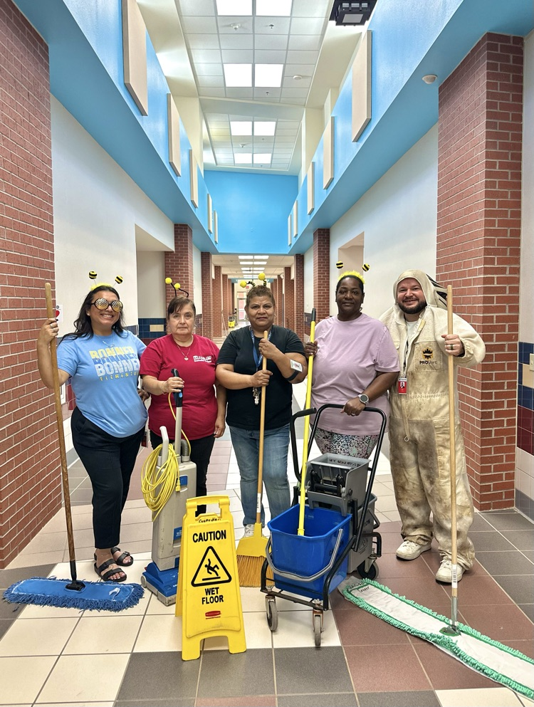 custodial staff posing with cleaning materials to welcome students back