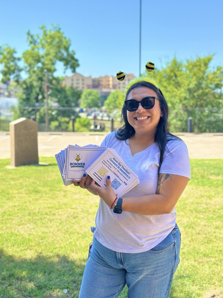 staff member holding assignement cards and smiling with a bee antennae diadem