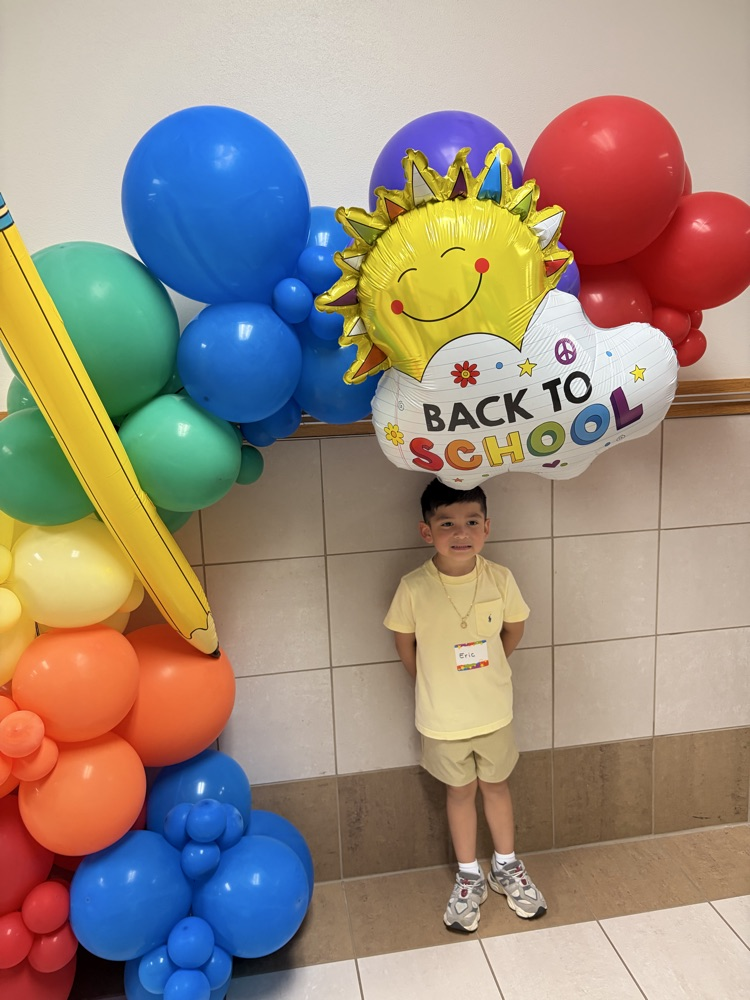 student posing under balloon arch