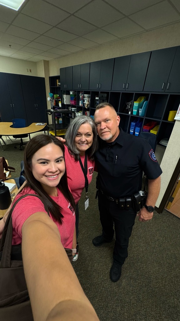 Three people standing in an office. Two women and a man. One man wears a police uniform.