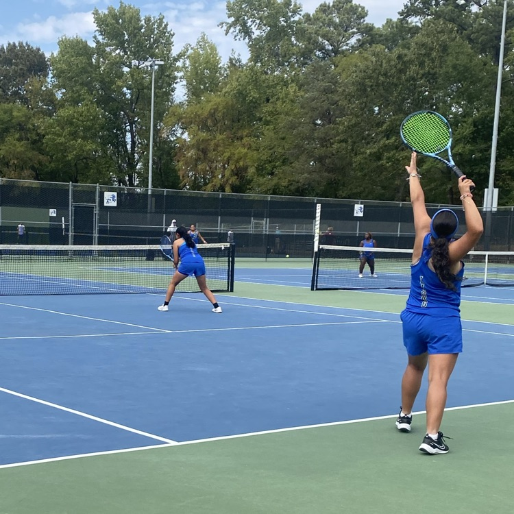 tennis doubles team serving the ball