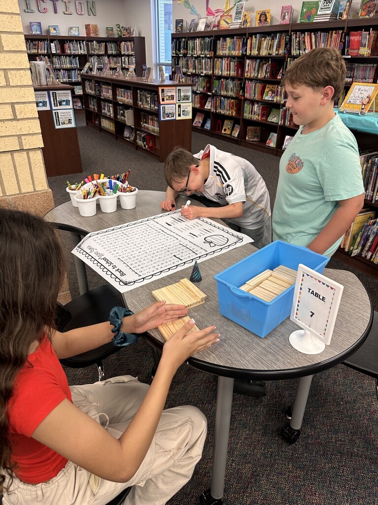 3 students doing a word search and build blocks at a table