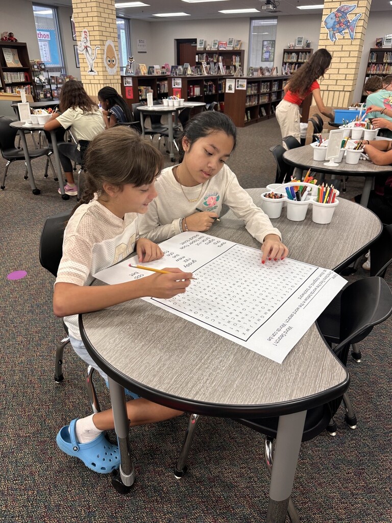 2 students completing a word search at a table
