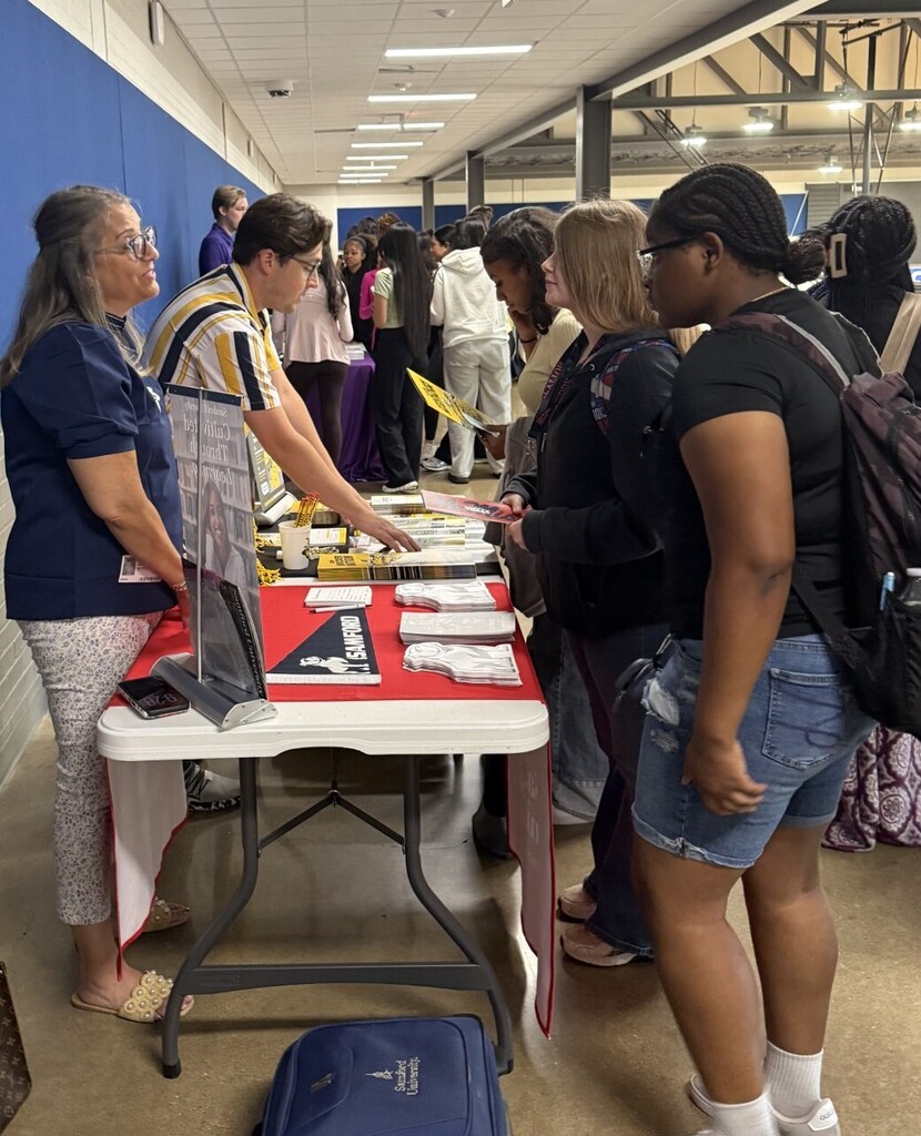 students at table talking to college representatives
