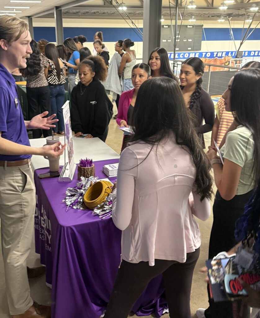 students at table talking to college representative