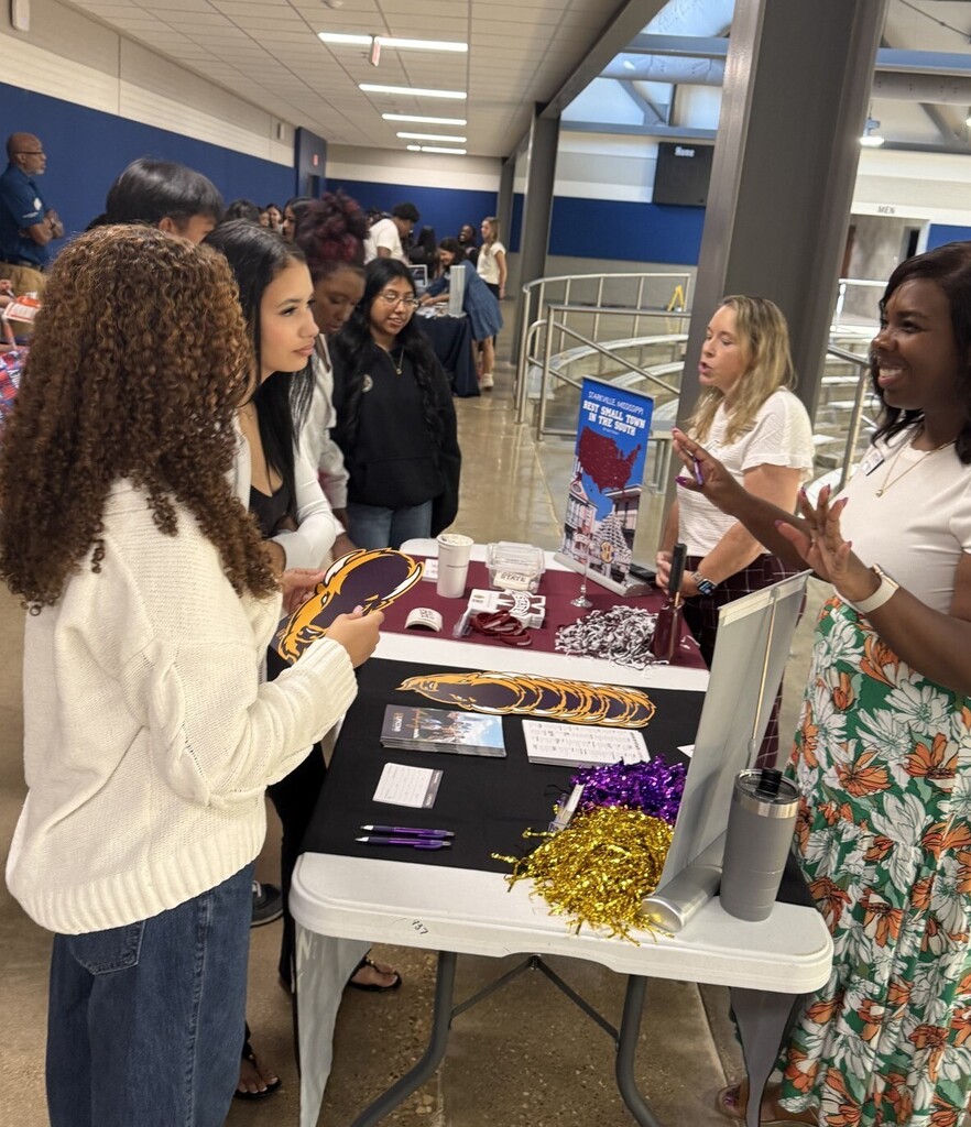 students at table talking to college representative