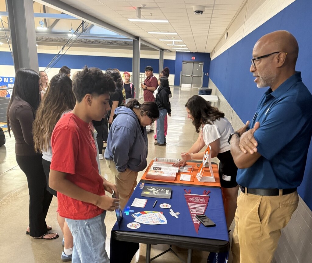 students at table talking to college representative