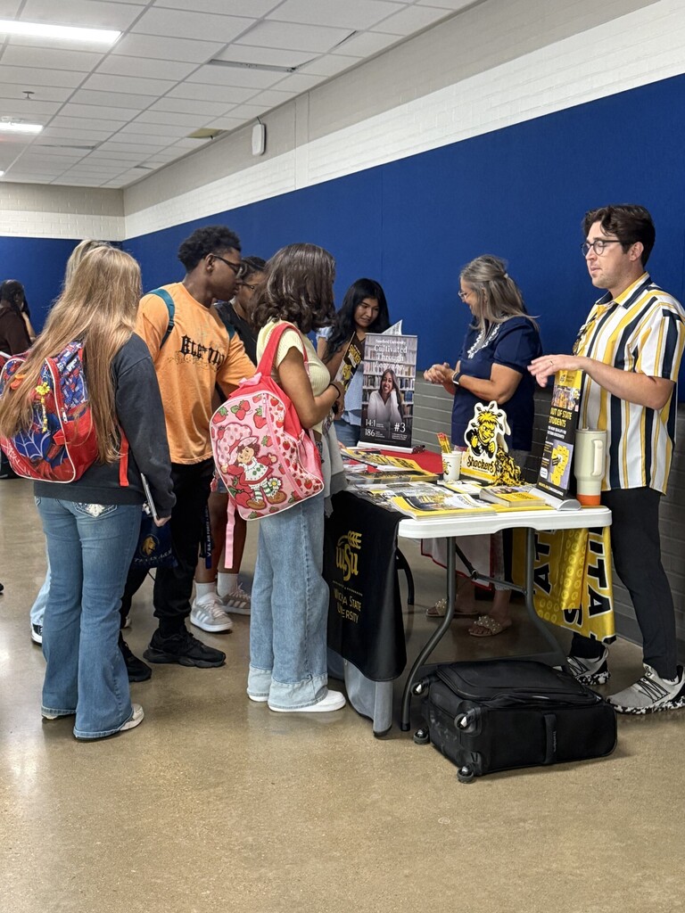 students at a table talking to college representatives