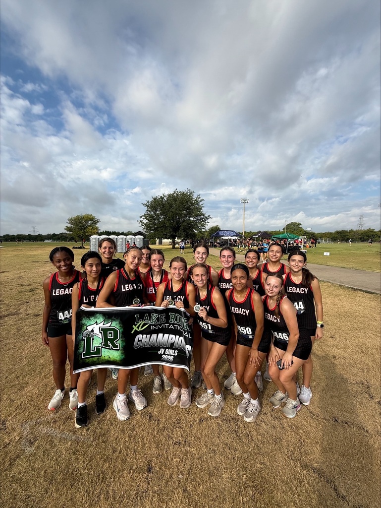 A group of women wearing black uniforms poses for a photo with a banner on a field.