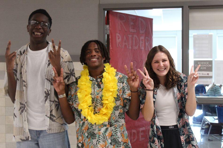 Three people smiling and making peace signs with leis. A pink banner behind them reads "RED PATROL."