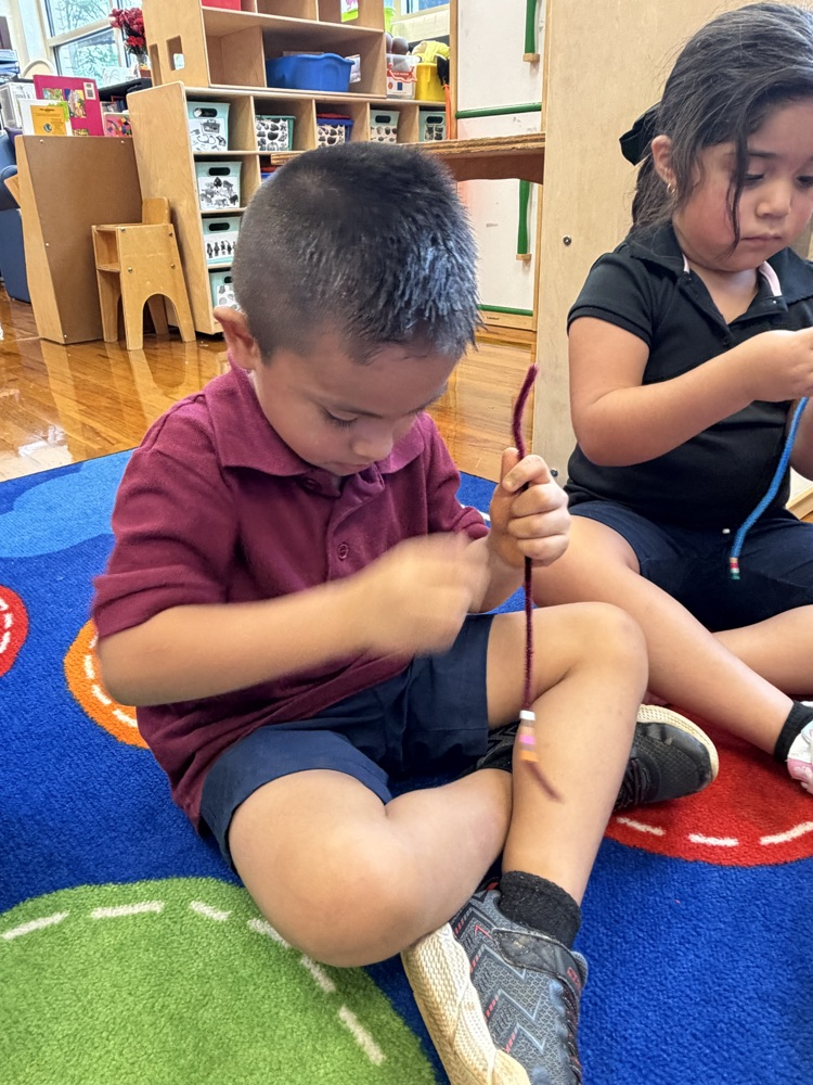 boy making a friendship bracelet on the rug