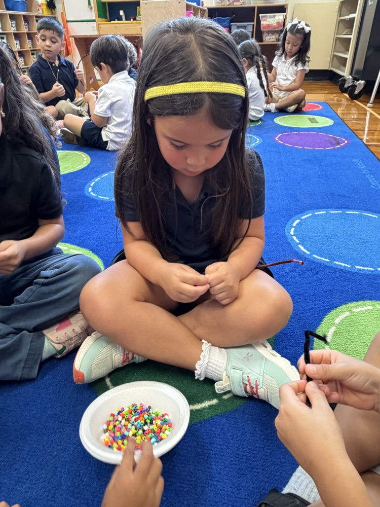 kids on rug with beads making bracelets