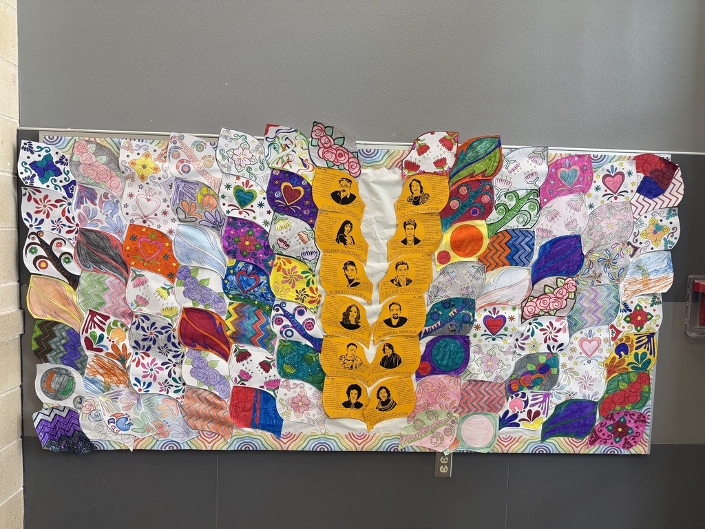 A colorful, hand-crafted quilt with multiple patches of various designs. The quilt has a series of faces in the center.