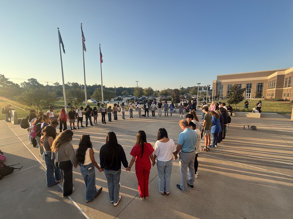 students and teachers praying around a flag pole