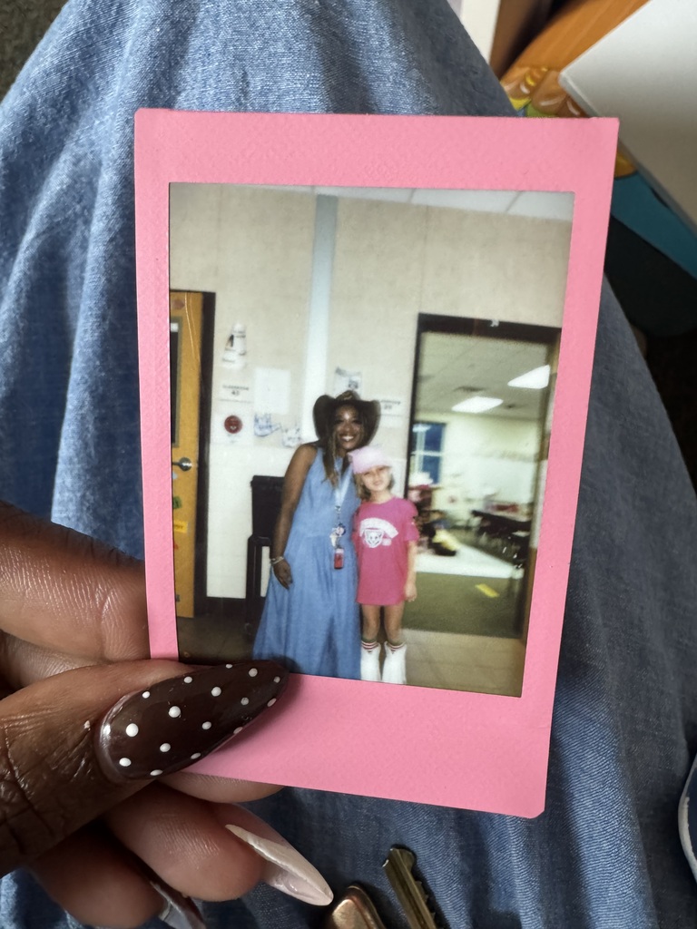 A Polaroid picture of a woman and a young child standing together indoors, displayed on a pink frame.