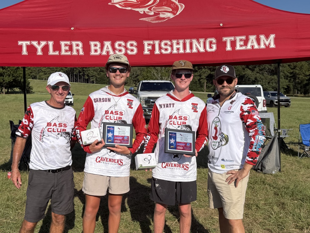 Four people in matching shirts, hats, and sunglasses pose under a red tent with "Tyler Bass Fishing Team" text.