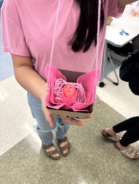 Student holding egg representing a baby in a basket