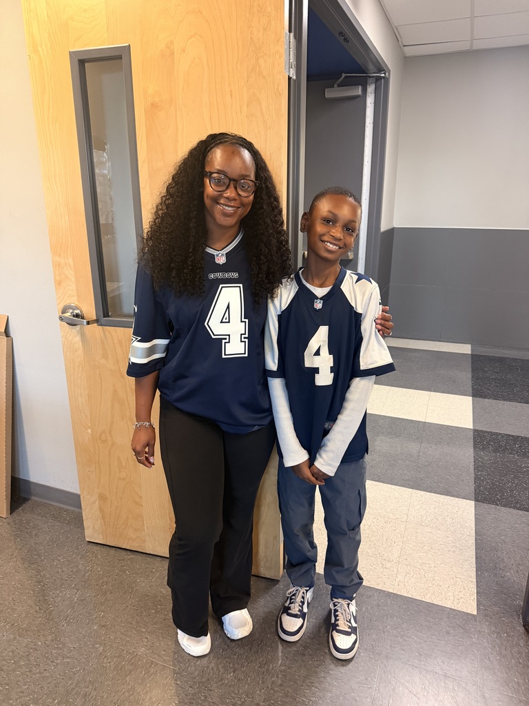 A woman and a child in matching blue jerseys with the number 4 stand in a hallway.