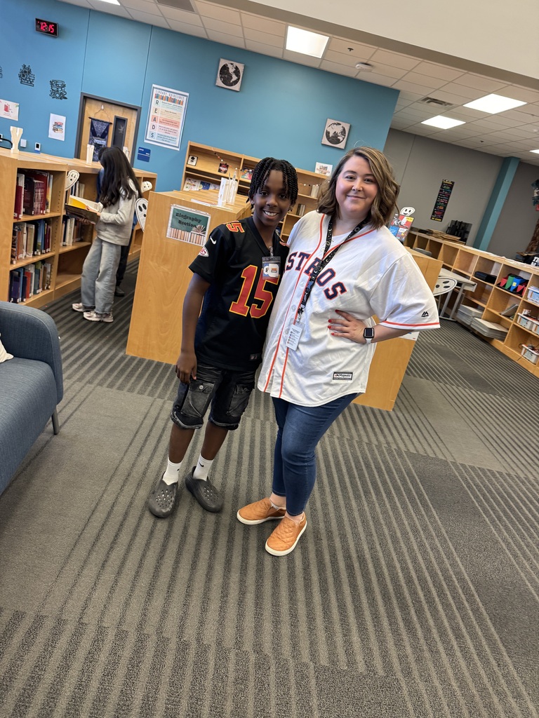 Two people in a library, one wearing a sports jersey with the number 15, the other in casual clothing.
