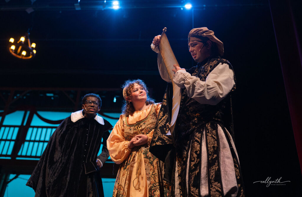 Three people on stage, one holding a piece of paper, another with a lute. Background with lighting.