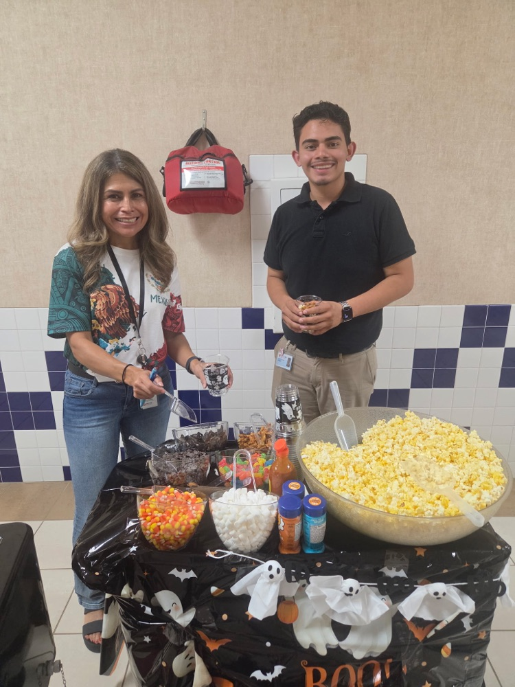 teachers posing behind popcorn cart