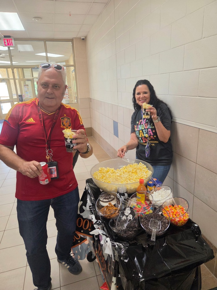 man and woman standing behind cart of popcorn and candy