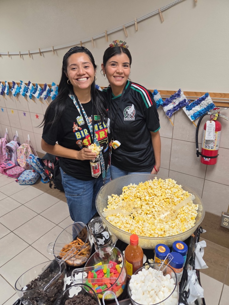 two teachers behind popcorn cart