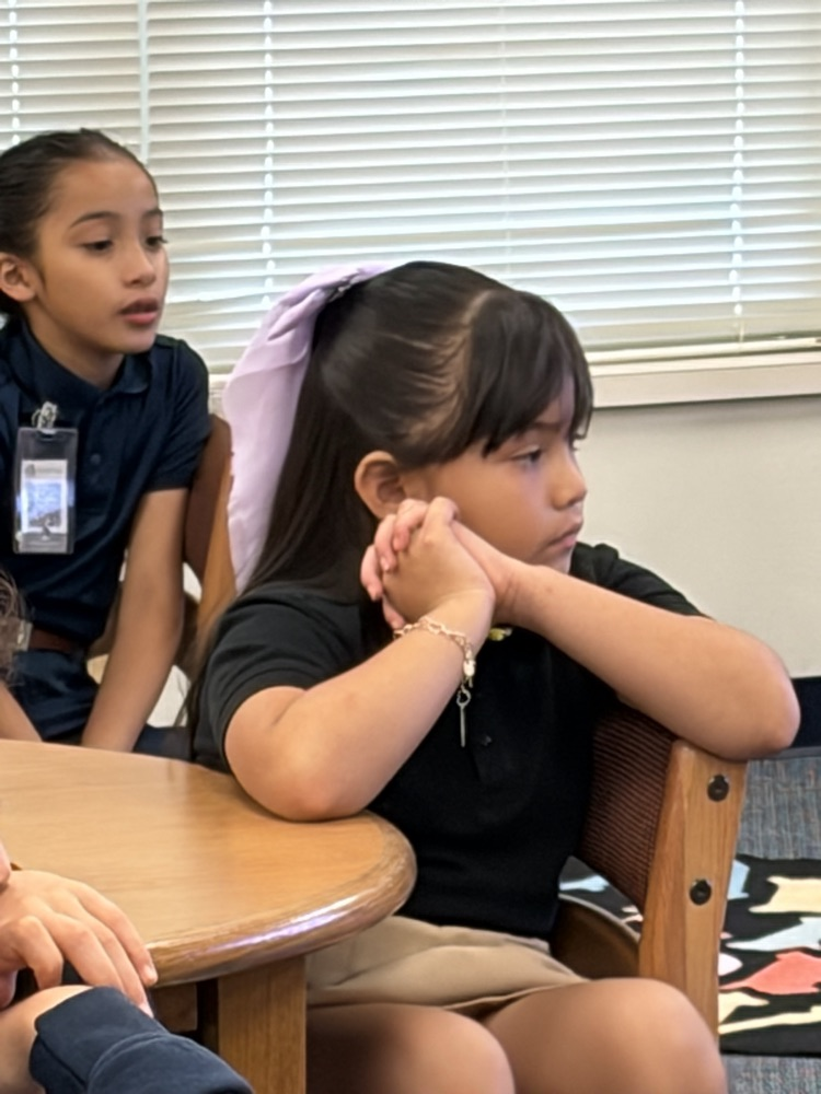 girls listening to book at a table