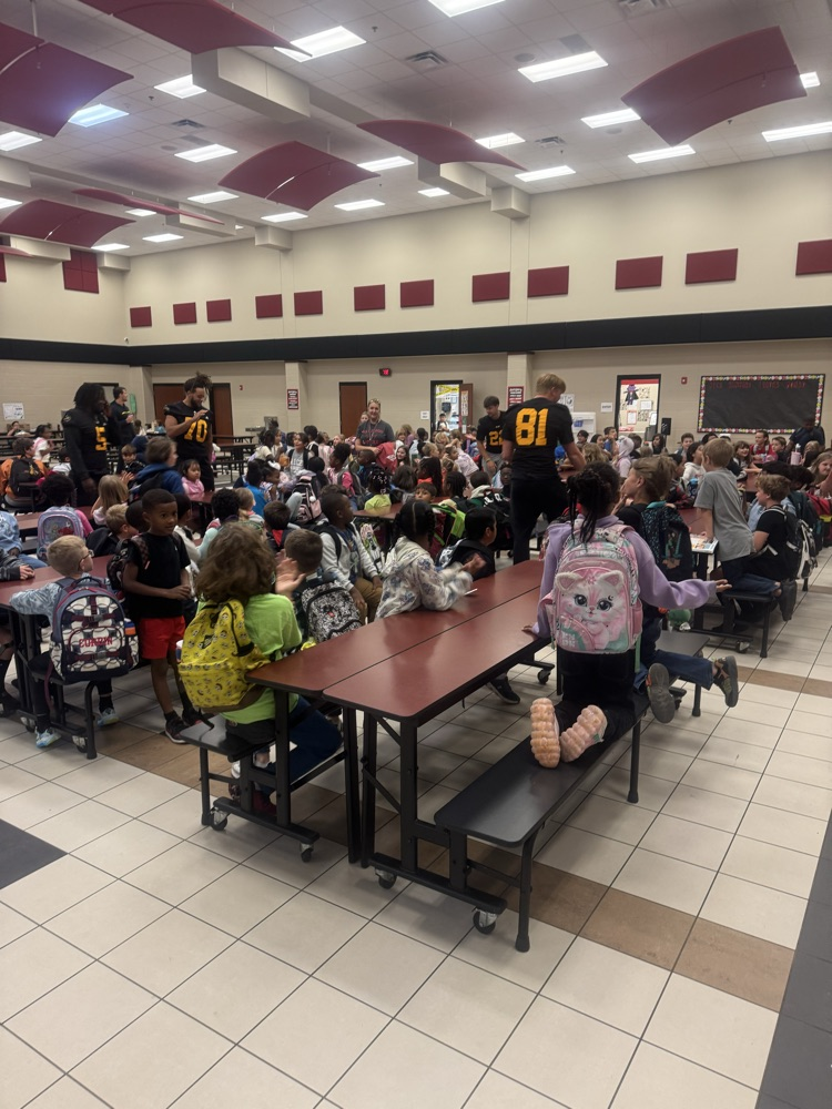football players giving kids high-fives in the cafeteria