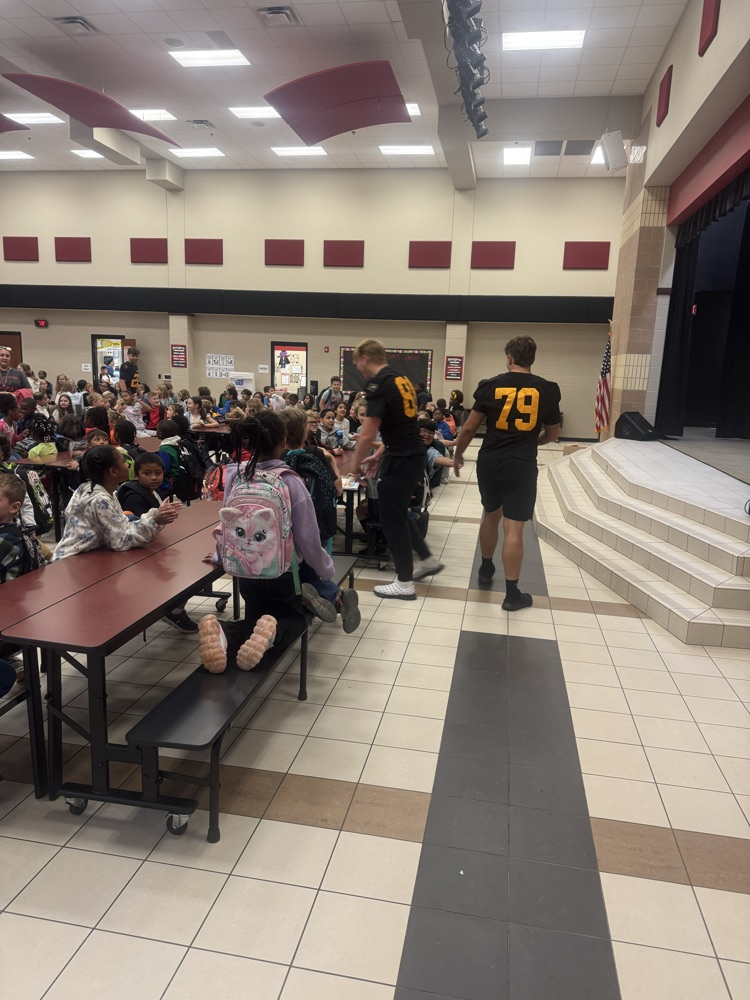 football players giving kids high-fives in the cafeteria