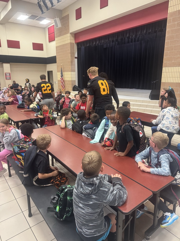 football players giving kids high-fives in the cafeteria
