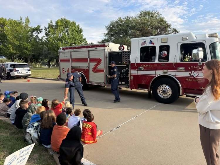students looking at a fire truck with firefighters