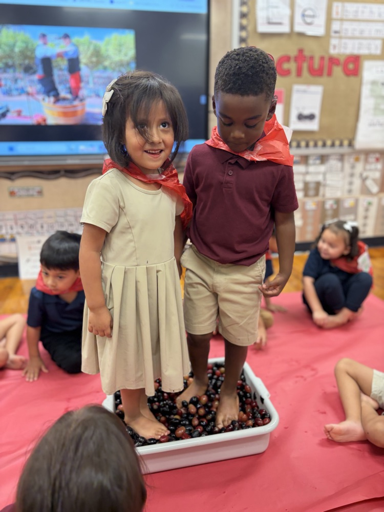 two kids stomping on grapes in a bucket