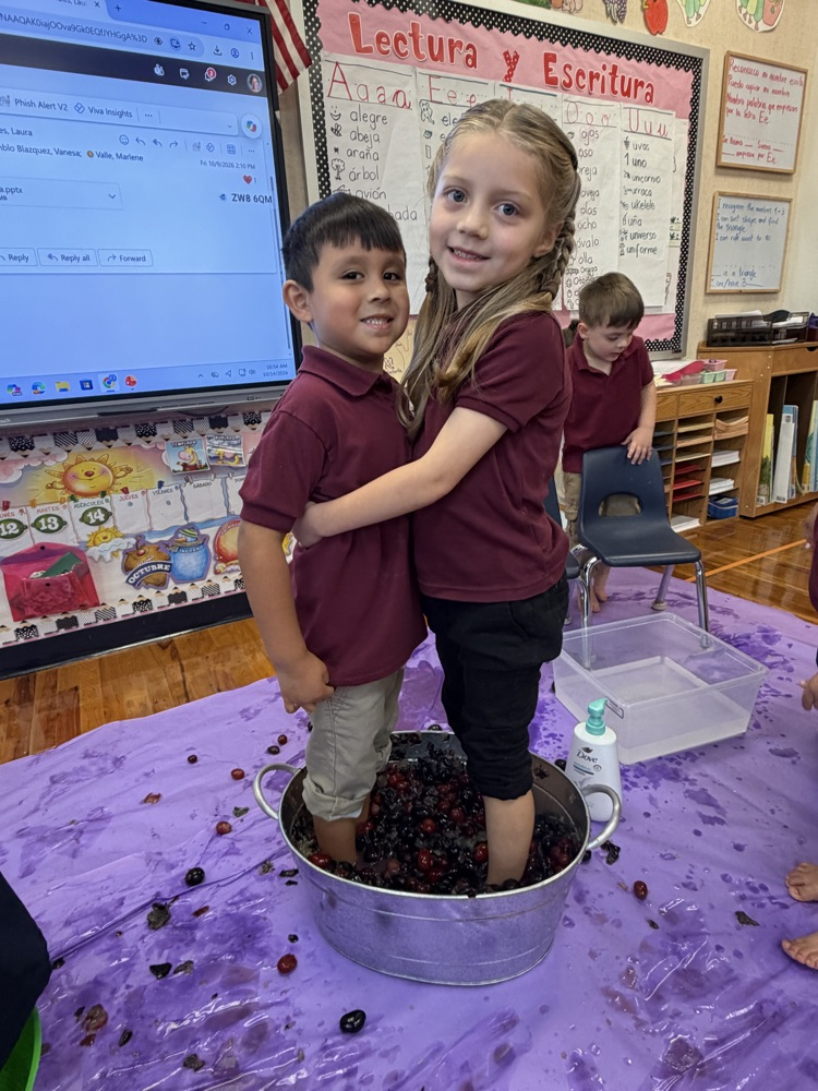 kids with their feet in a silver bucket, stepping on grapes