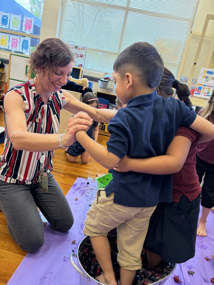 teacher helping children step on grapes