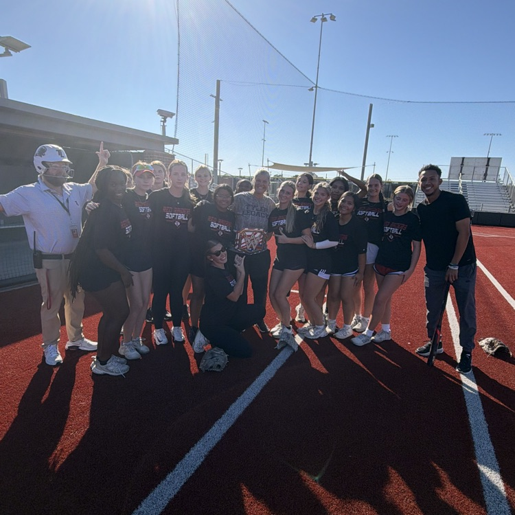Group of people on a track field; some in black shirts, some in white shirts.