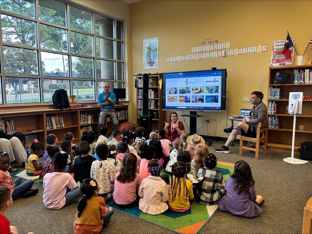 pre- students sit on a carpet to learn about hand washing by a visitor