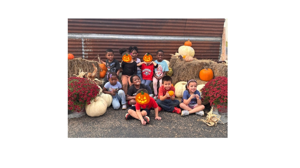 students smile while sitting on the hay bales at the pumpkin patch