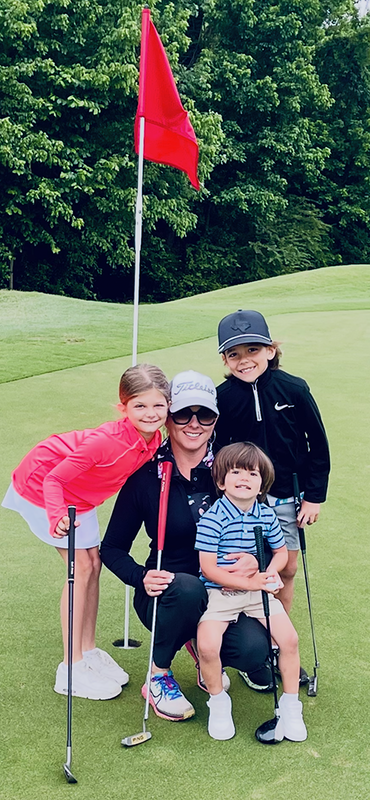 woman with two boys and a girl holding golf clubs by a flag