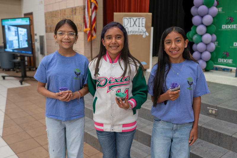 girls standing in cafeteria holding cupcakes