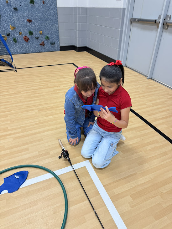 elementary kids looking at a plastic fish in a gym