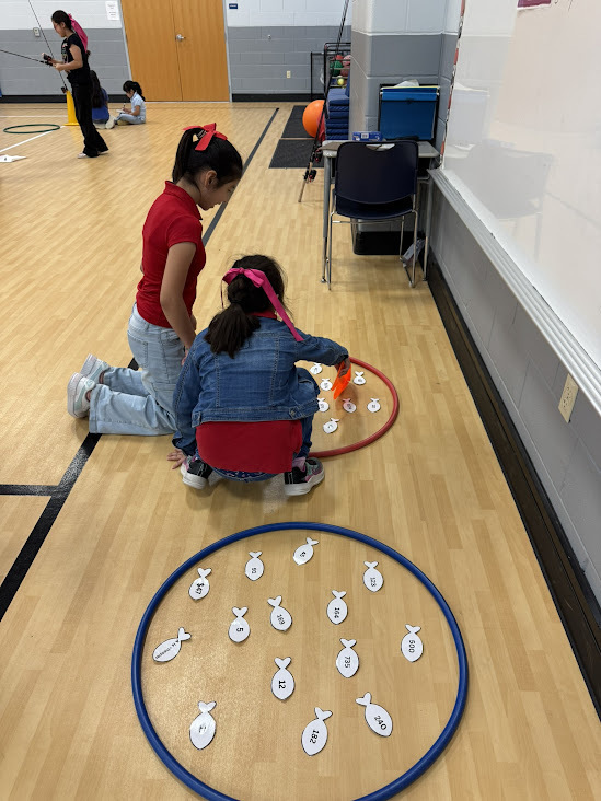 elementary kids counting plastic fish in a hoola hoop in a gym