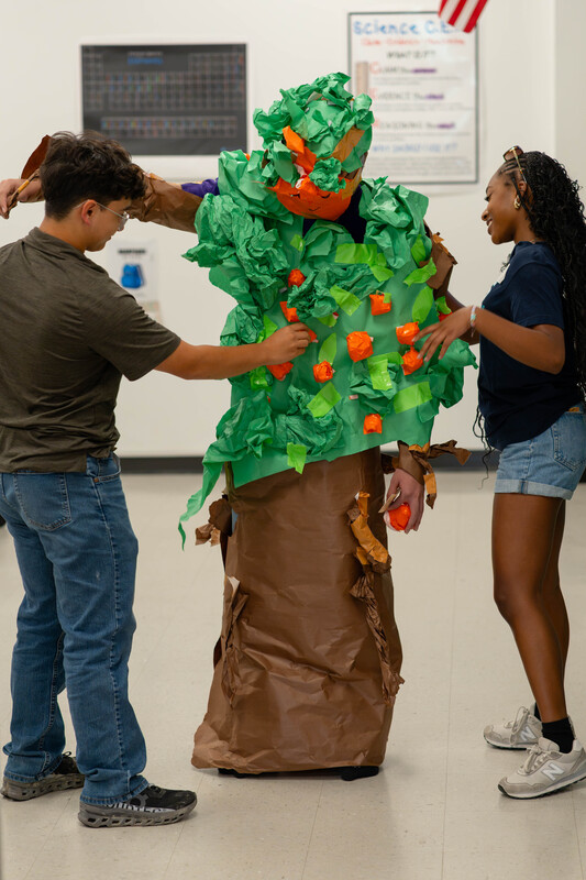 teen boy and girl dressing another teen up like a tree