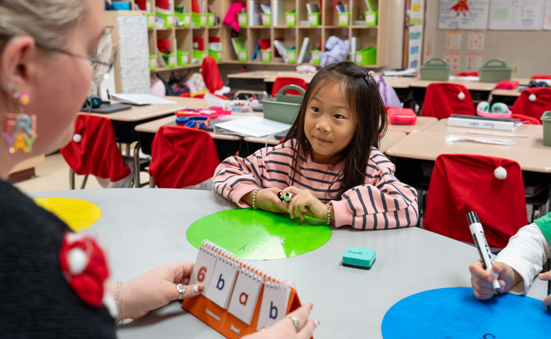 woman at desk with young child working on class project