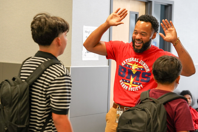 man showing excitement with big smile and arms in the air as he welcomes teens back to school
