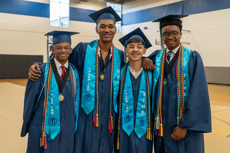 four teen boys in their blue graduation caps and gowns