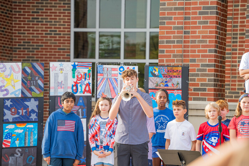 teen boy playing Taps with younger kids standing behind him