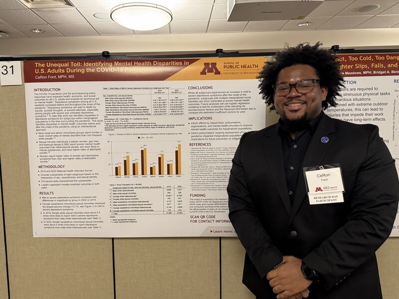 African American man standing next to wall with graphs and data posted on it