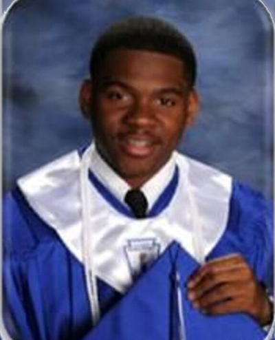 African American teen boy in blue graduation gown with white stole holding his blue cap